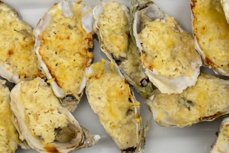 Plusieurs huîtres chaudes et ouvertes, gratinées avec du fromage.