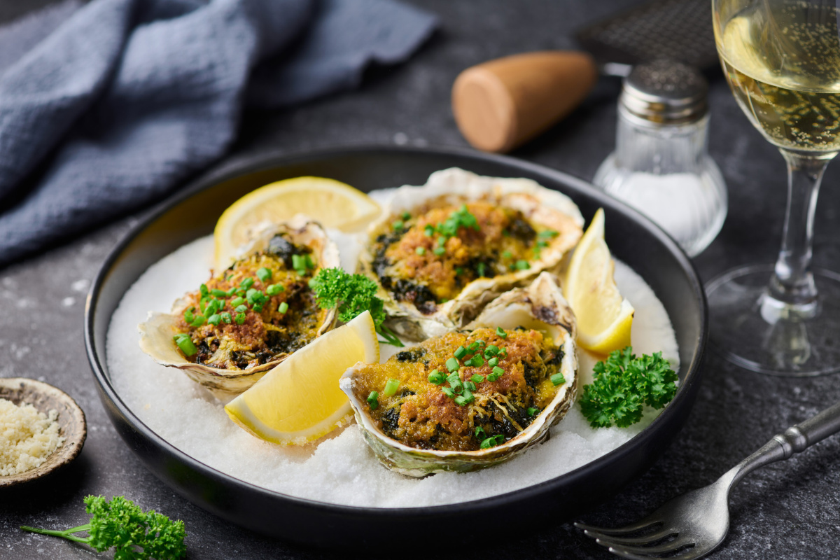 Huîtres Rockefeller gratinées aux herbes, servies avec des quartiers de citron frais.