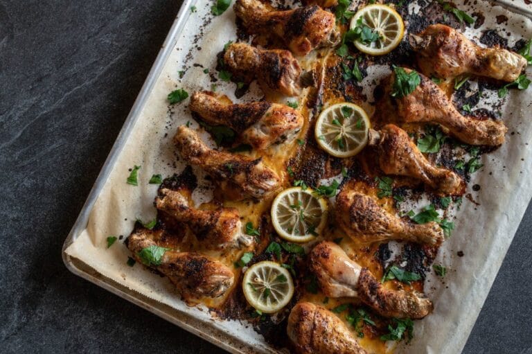 Pilons de poulet martinés et rôtis au four, garnis de rondelles de citron et persil.