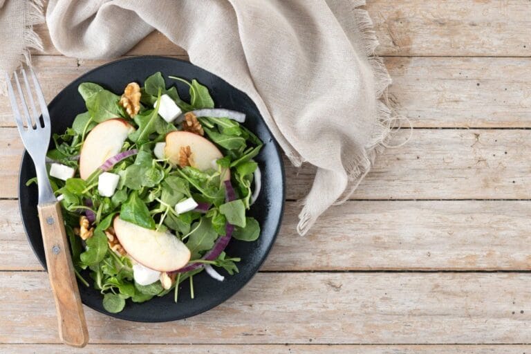 Salade d'automne composée avec des pommes, des noix et des cubes de feta.