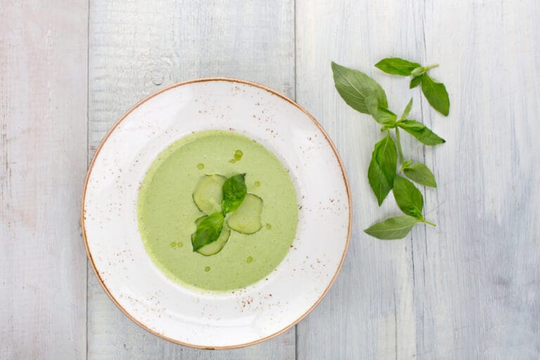 Soupe froide de concombre avec du basilic frais et des rondelles de concombre.