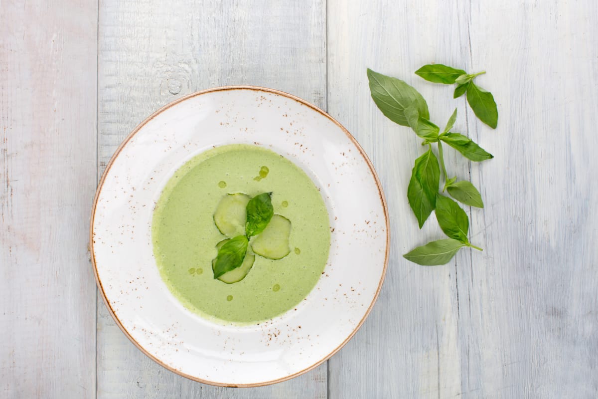 Soupe froide de concombre avec du basilic frais et des rondelles de concombre.